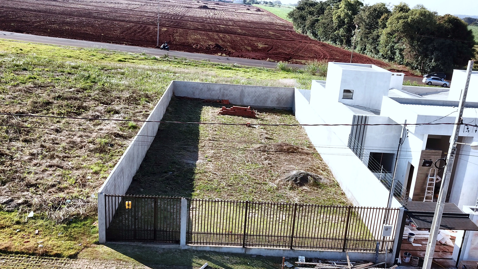 Lote murado com grade preta antes do início da residência